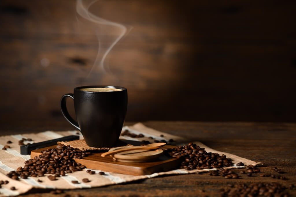 ფინჯანი ყავა კვამლით და ყავის მარცვლებით