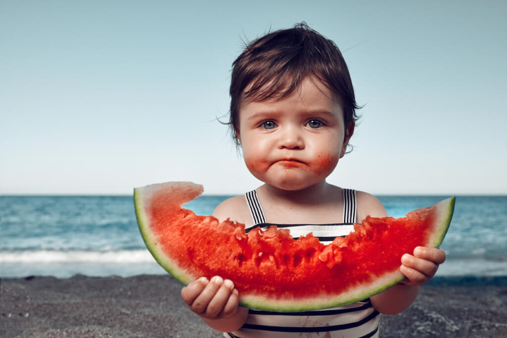 child eats watermelon with a dissatisfied face