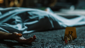 A Corpse Lying on the Floor and Covered. Accidental Manslaughter Leaving Young Man for Dead. Glasses and Blood Marked as Evidence Next to the Corpse