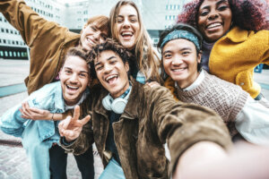 Multiracial friends taking selfie pic outdoors - Happy young people having fun walking on city street - Life style concept with guys and girls hanging outside - College students smiling at camera
