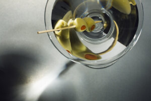 A chilled Martini garnished with two pimento stuffed green olives skewered by a toothpick, seen from a stylish overhead view.