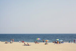 Diverse group of people enjoy day at the beach. People of all ages, sizes and color enjoy the beach. Rocking their swimsuits, bikinis and street wear.
