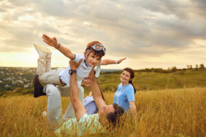 Happy family playing on grass in nature at sunset