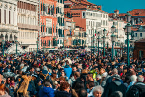 Crowds of tourists walking by typical venetian buildings near San Marco Square during famous traditional carnival taking place each year in Venice, Italy.