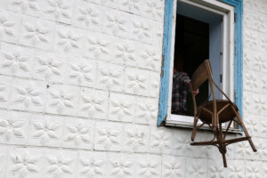 A man throws an old chair out of the window