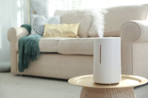 Modern air humidifier on table in living room. Space for text
