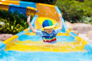 Kids on water slide in aqua park. Children having fun on water slides on family summer vacation in tropical resort. Amusement park with wet playground for young child and baby.
