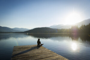 Woman doing sunrise yoga on Alta Lake in Whistler, Canada. Yoga and wellness themes.