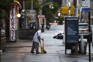 An Italian restaurateur is cleaning the sidewalk in front of his Italian restaurant in Little Italy. Manhattan, New York City, United States. Little Italy is a general name for an ethnic enclave populated primarily by Italians or people of Italian ancestry, usually in an urban neighborhood.