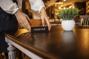 Restaurant Chilling Out Classy Lifestyle Reserved Concept. Waitress reserving a tablet at a restaurant and putting a sign on the table - food service concepts