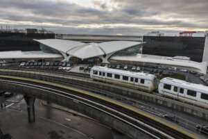 JFK International Airport, one of the busiest in the world, is active even in stormy weather in early morning. Airtrain is going to the Terminal 5, with stuffed parking lot.
