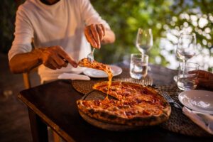 Man and woman having pizza for dinner at the romantic restaurant outdoors.