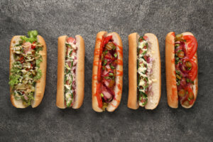 Delicious hot dogs with different toppings on grey table, flat lay