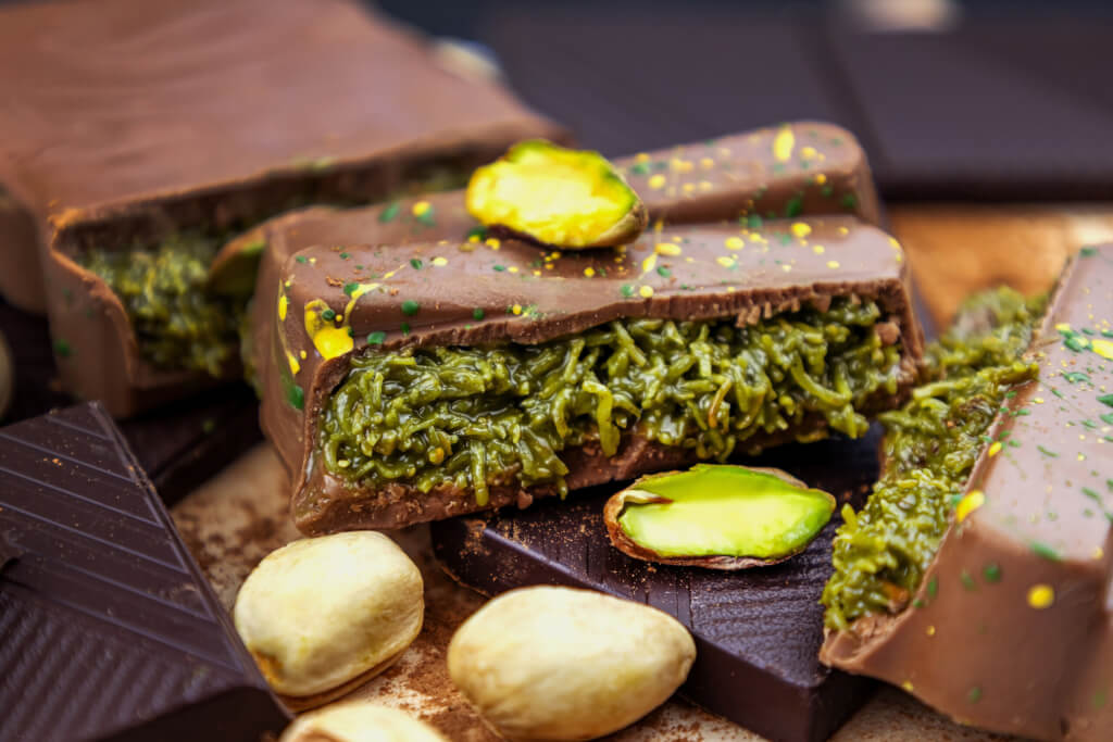 Dubai Chocolate bar with green kadayif and pistachio spread with pistachio nuts close up
